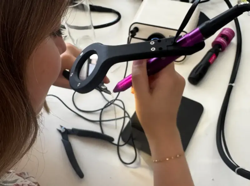 Teilnehmerin übt Feinschweißen mit Stylus, Zange und Eclipse Sichtschutz bei einer Permanentschmuck Schulung